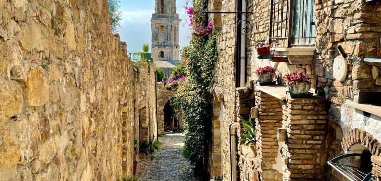 Vue pittoresque d'une ruelle en pierre pavée menant au clocher historique de Ceriana, un village authentique de l'arrière-pays ligure choisi